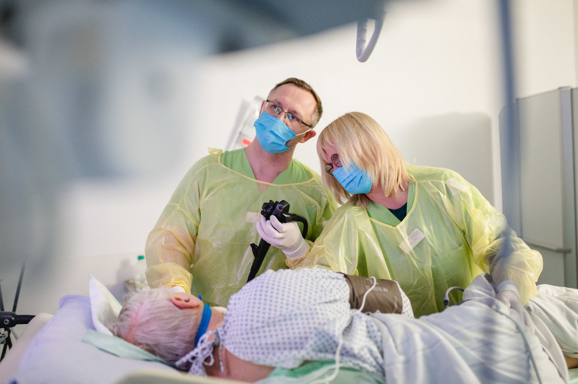 Patient wird in der Liegeposition von zwei Ärzten untersucht, Bereich Gastroenterologie